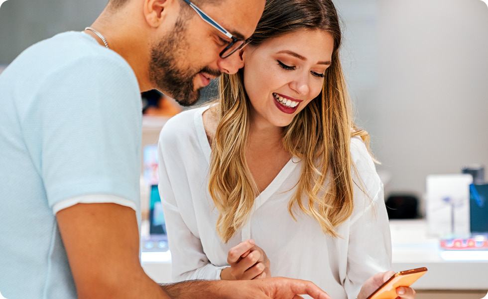 man and woman looking at cell phone deciding on purchase